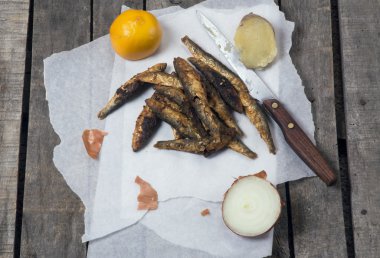 Limon, soğan ve patates ile beyaz kağıt üzerinde kızarmış smelts