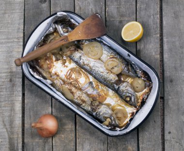 Soğan ve masada yarım limon ile fırında uskumru balık