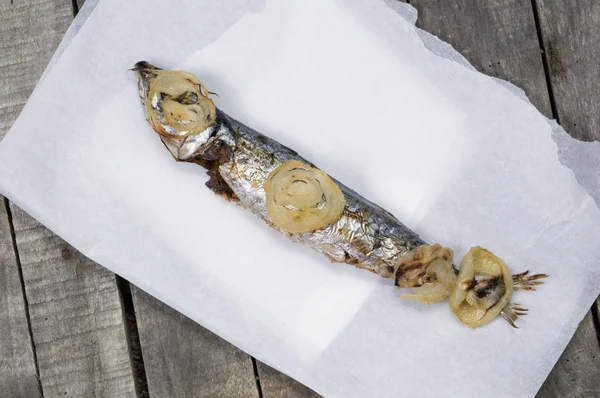 One baked mackerel fish on white paper and wooden background — Stock Photo, Image