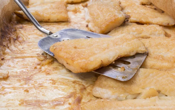 Detalle de los filetes de bagre asado al servir cuchara en una bandeja para hornear — Foto de Stock