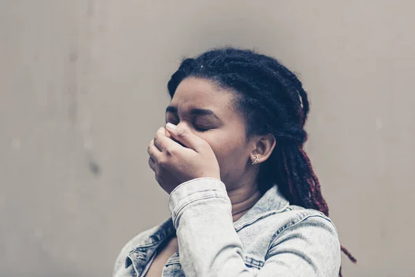 A young black woman covers her mouth to keep her mouth shut. The emotion of despair and self-control