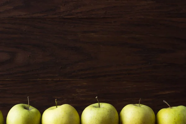 green apples on a wooden background. Apples lined up in a row