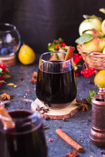 Hot wine with spices in glass glasses. Mulled wine with cinnamon and star anise on a table with fruit