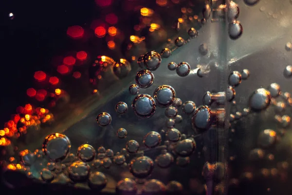 Air bubbles on a piece of ice in a liquid soda