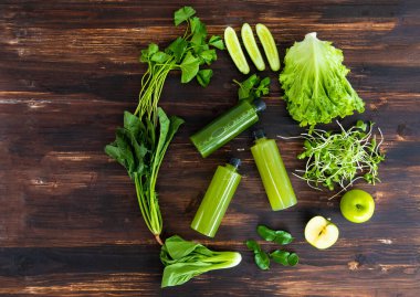 Çeşitli sebze bileşenleri yeşil sağlıklı meyve sularını yukarıdan bakıldığında antika bir ahşap masaya koyar. Yaşam tarzı, diyet, detoks, vücut temizleyici gıda konsepti..