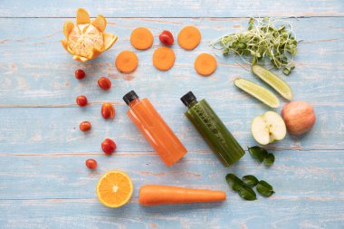 Karışık sebze ve baharatlardan oluşan bir şişe sağlıklı meyve suyu ve kırsal bir ahşap masanın etrafına konan malzemeler. Sağlık, doğal gıda, diyet ve detoks kavramı.