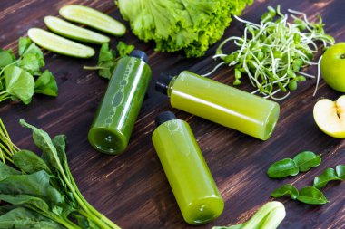 Çeşitli sebze bileşenleri yeşil sağlıklı meyve sularını yukarıdan bakıldığında antika bir ahşap masaya koyar. Yaşam tarzı, diyet, detoks, vücut temizleyici gıda konsepti..