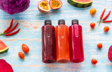 Meyve, baharat ve sebzelerin çeşitli malzemelerinden elde edilen birkaç şişe ev yapımı meyve suyu yüksek açılı ahşap masa üzerinde. Sağlık yaşam tarzı detoks ve diyet gıda ve içecek konsepti.