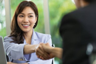 Çekici Asyalı genç başvuru yapan kadınla iş görüşmesinden sonra personel ofisinde el sıkışma fotoğrafı. Kariyer başvurusu ve tebrik kavramı.