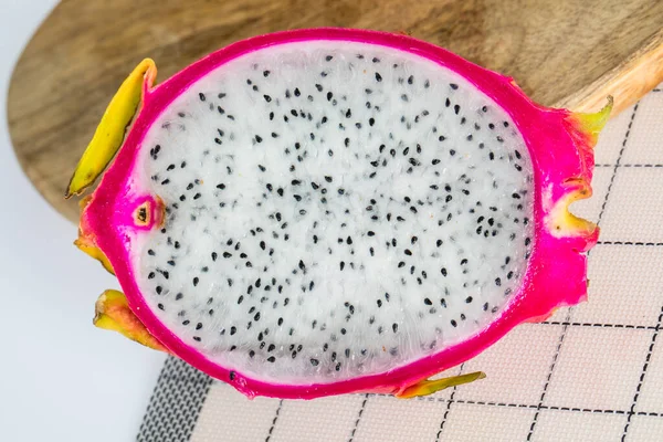 Delicious and fresh-cut dragon fruit with black seeds white flesh on mat wooden tray and white table. Have good nutrition and medicinal for healthy.