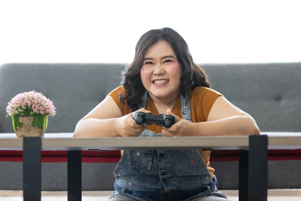 明るい脂肪アジアの女性が座っていると喜びと自宅で休日にコンピュータゲームをプレイ見てジョイスティックを保持の肖像画 女性の顔を中心に — ストック写真
