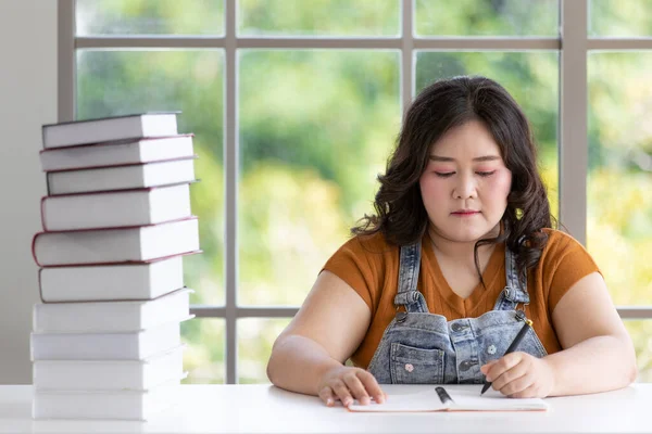 Толстая Азиатка Студентка Концентрацией Сидя Держа Руках Ручку Пишущую Столе — стоковое фото