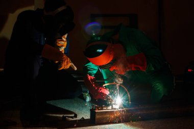 Tamirciler geceleri fabrikada fazla mesai yapmazlar. Tamirci tulumları, eldivenleri, botları ve metal kaynaklama kaskları olan güvenlik kıyafetleri giyen mühendisler..