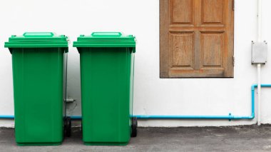 Yaya yolunda ve beyaz beton duvarda kullanılmaya hazır yeni açılmış yeşil büyük kutular..