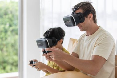 Kafkasyalı baba ve melez oğul joystick 'i tutuyorlar ve birlikte oyun oynuyorlar. Eğlenceli ve mutlu bir şekilde..