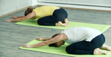 İki beyaz kadın Yoga oyuncusu vücut esneme hareketleri yapıyor ve birlikte alıştırma yapıyorlar. Kişisel sağlık ve beden ve zihin dengesi için fikir.