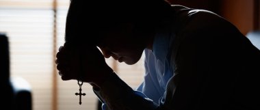 Asyalı bir adam İncil 'e başını eğip haç taşıyor. Hristiyanlığın inançlarına göre İsa 'nın kurtuluşu. Ve Tanrı 'nın koruması için dua et. Dua isteğini kabul et