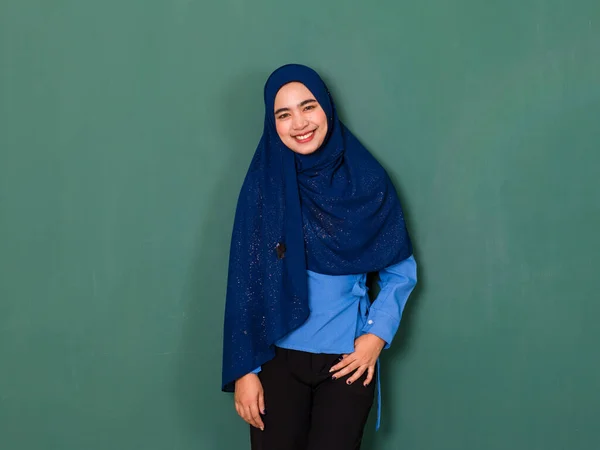 若い幸せな笑顔の肖像画自信を持って美しいイスラム教徒の女性はよく身に着けている青いヒジャーブ立っていると緑の背景の上にカメラを見て — ストック写真