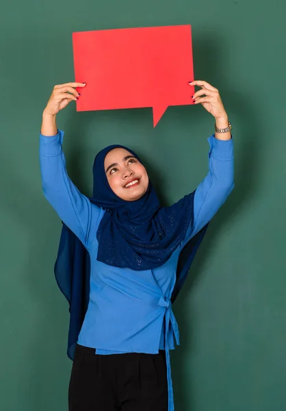 自信と幸せな女性の概念 かなり魅力的なイスラム教徒の女性は美しく身に着けている青いヒジャーブ立っていると緑の背景に黄色の空白のスピーチバブルを保持 — ストック写真