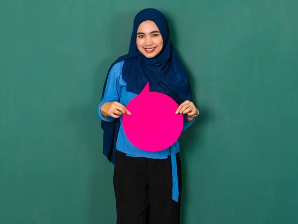 自信と幸せな女性の概念 かなり魅力的なイスラム教徒の女性は美しく身に着けている青いヒジャーブ立っていると保持ピンクの空白のスピーチバブル上の緑の背景 — ストック写真