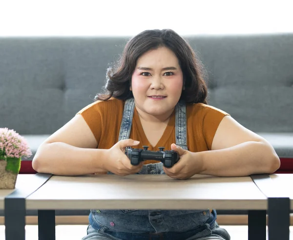 自宅で休日に真剣にゲームをプレイ中に脂肪アジアの女性が座って コンピュータ画面を見てジョイスティックを保持するの肖像画 女性の顔を中心に — ストック写真