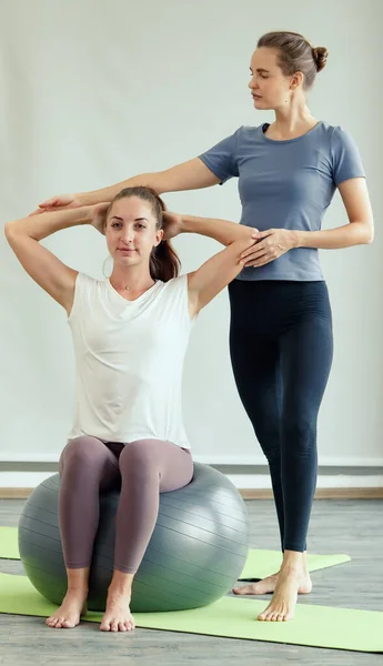 Two Caucasian good shape female Yoga players doing body stretches and practice together. Idea for self healthcare and balance of body and mind.