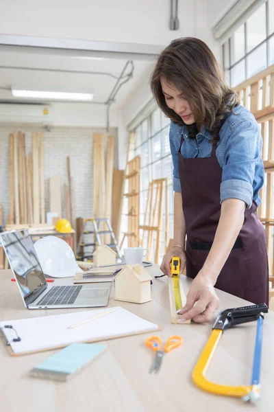 Kot pantolon giyen güzel Asyalı kadın evde marangoz olarak çalışıyor. Marangozluk ve rahatlama hobileri için ahşap işçiliği ve ucuz işleri seven insanlar için konsept..
