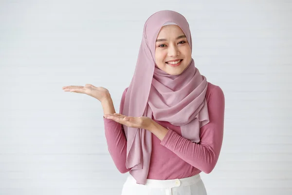 自信を持ってカメラにポーズをとるフレンドリーで暖かい笑顔で美しいイスラム教徒の女性の肖像画 広告のジェスチャーでポイント指 — ストック写真