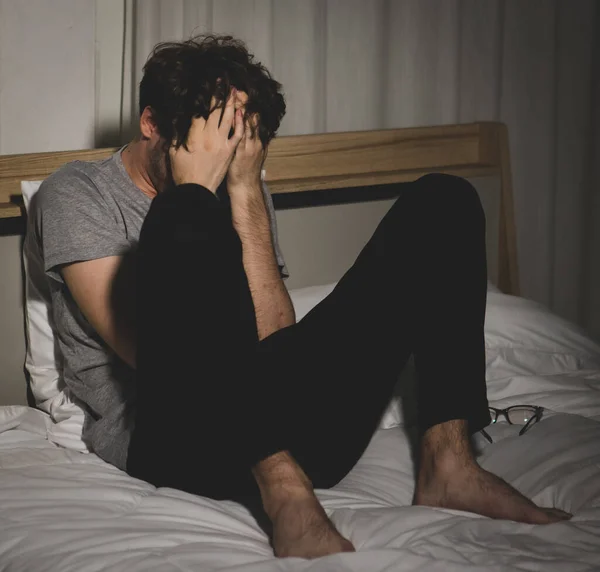 ストレスと動揺若い白人男性気軽にベッドの手を頭を保持に座って服を着た 破産の概念 — ストック写真