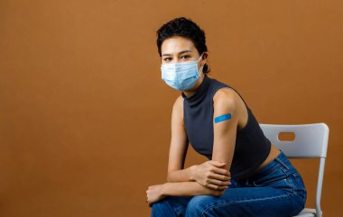 Kendine güvenen güzel ve seksi bir kadın hastanın portresi Coronavirus Covid-19 aşısı olduktan sonra omuzlarında maske takıyor..