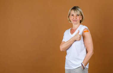 Kafkasyalı yaşlı sarışın hastanın portresi. Kameraya bak. Coronavirus aşısı olduktan sonra omzunda turuncu bandaj var..