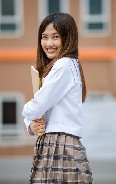 若い魅力的な女性アジアの高校生の肖像白いシャツ茶色の小学校制服保持文書ファイルで学校のキャンパス — ストック写真
