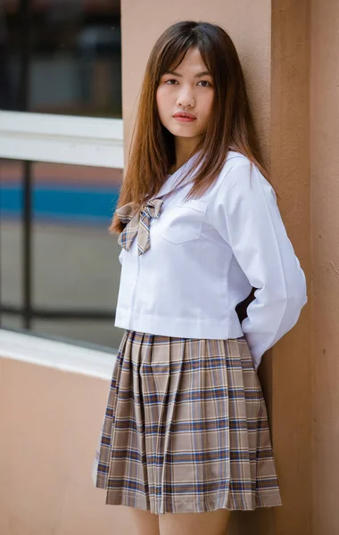 校园里穿着白衬衫 棕色格子校服的年轻漂亮的亚裔女高中生的画像 — 图库照片
