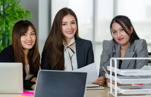 オフィスのカメラで笑顔に座って正式なビジネススーツで3つの魅力的なアジアの女性のオフィスの同僚のグループ 近代的な事務所業務の概念 — ストック写真