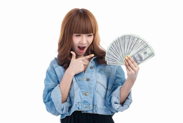 棕色头发的亚洲女人拿着并指着手中摊开的美国钞票 微笑着 在白色背景下拍摄着电影 — 图库照片