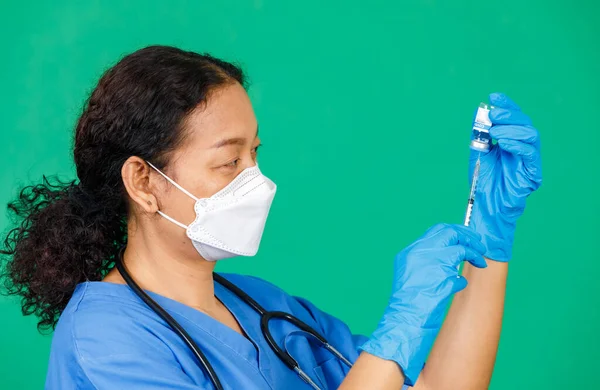 Asian female nurse in scrubs wearing mask holding syringe and Covid 19 vaccine preparing for injection. Concept for Covid 19 vaccination.