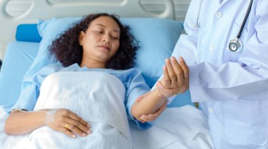 Doktor, hastanedeki Asyalı kadın hastanın elini tutuyor ve tedavi ve tedavi için sinir sistemini kontrol ediyor. Guillain barre sendromu kavramı ve uyuşmuş el hastalığı veya aşı yan etkisi.