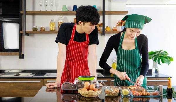 줄무늬 앞치마와 모자를 아시아 출신의 요리사는 닭고기 소시지를 카운터에서 자르는 — 스톡 사진