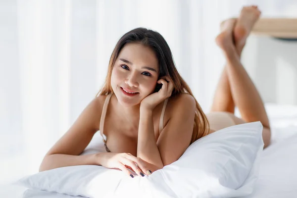 브라를 예쁘고 버릇없는 아시아 소녀가 침대에 베개를 아침을 열정적 미소를 — 스톡 사진