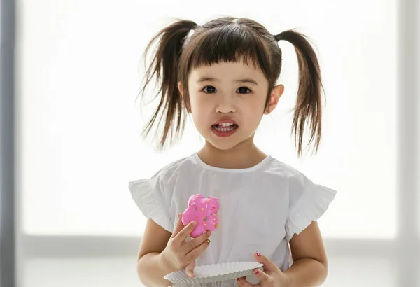 亚洲甜美可爱可爱快乐的幼儿园小女孩的特写特写照片 她有束发 站在镜头前 手里拿着纸盘 吃着美味的草莓味冰镇面包 — 图库照片