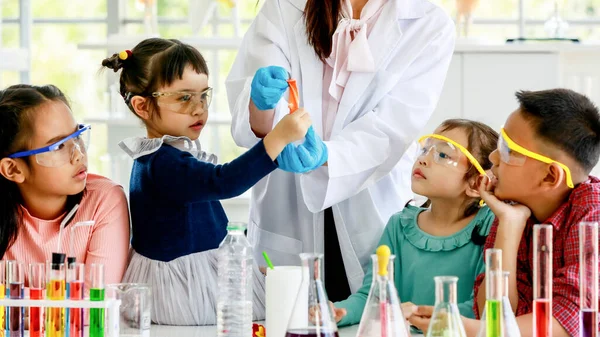 코트를 고무장갑 안경을 아시아 과학자가 시험관 현미경으로 실험실에 초등학생 여학생들에게 — 스톡 사진