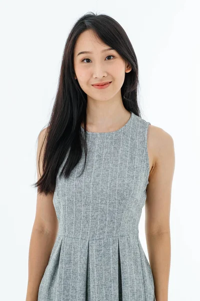 現代の若いアジアのビジネス女性長い黒髪中国の目スリム見えるスマートでカジュアルスタイルによってグレーノースリーブドレス笑顔立ってカメラを見て白い背景 — ストック写真