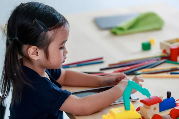 스트레스 가걱정되는 아시아 스타일 유치원 여학생은 책꽂이에 플라스틱 장난감 태블릿을 — 스톡 사진