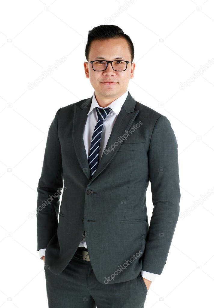Young and handsome businessman wearing dark gray suit and eyeglasses standing with friendly face and self-confidence with hand in pocket.
