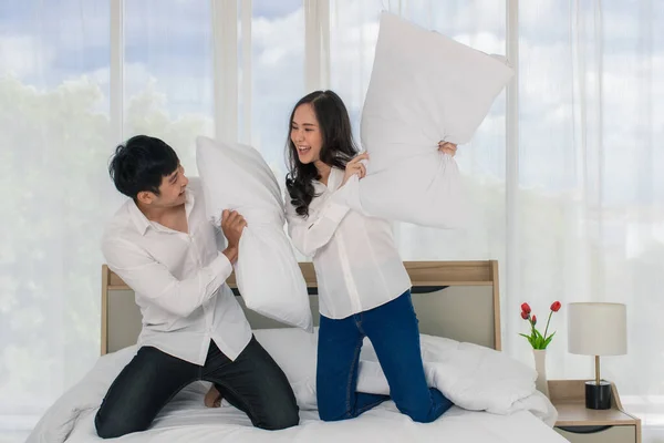 若い幸せな魅力的なアジアのカップルは ベッドの上で枕の戦いでお互いにからかう 白いカーテンの背景 愛と幸せな関係の概念 — ストック写真