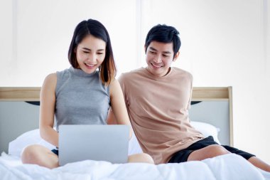 Mutlu, genç Asyalı çift evde boş vakit geçirirken dizüstü bilgisayarda oturup film izliyorlar.