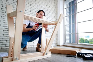 Tamirci olarak çalışan genç hippi, ahşap masayı malzemelerle birleştiriyor, ev yapımı ve self servis konsepti. Ofiste..