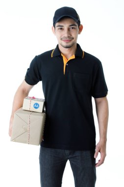 Neşeli Asyalı teslimatçı paketi iki elinde tutuyor, kameraya gülümsüyor. İzole edilmiş beyaz arka planda siyah üniformalı kurye portresi. E-ticaret iş konsepti