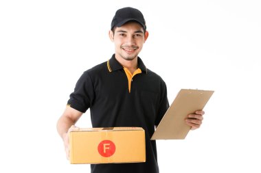 Çekici Asyalı teslimatçı paketi sağ elinde ve teslimat kağıdı sol elinde tutuyor. İzole edilmiş beyaz arka planda siyah üniformalı kurye portresi. E-ticaret iş konsepti