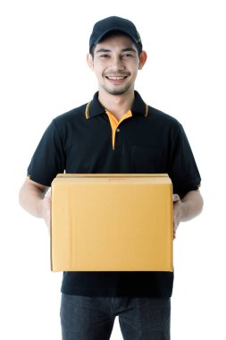 Neşeli Asyalı teslimatçı paketi iki elinde tutuyor, kameraya gülümsüyor. İzole edilmiş beyaz arka planda siyah üniformalı kurye portresi. E-ticaret iş konsepti